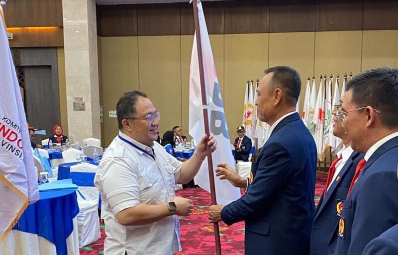 Poto: Ketua KONI Lampung, Tofik Hidayat, menyerahkan bendera petaka kepada ketua Ketua PBPI Lampung, H. Tomy Rianta Putra tanda masuknya PBPI di KONI Lampung ( ist ).