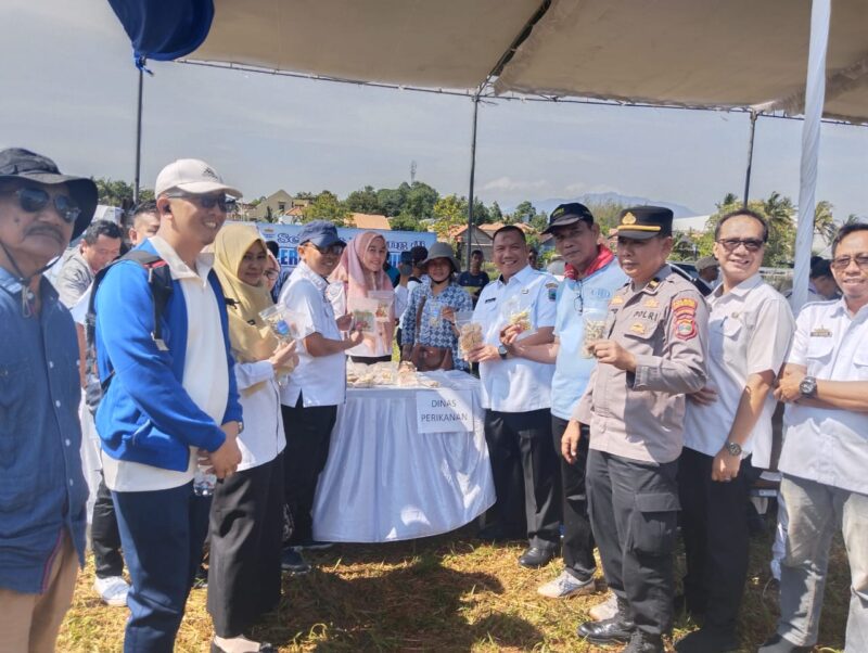 Plt Asisten Ekobang Setdakab Lamsel Wahidin Amin dan  Kepala Disdagprind Lamsel Hendra Jaya tengah menunjukan hasil olahan Dinas Perikanan yang dijual pada Operasi Pasar Murah, di Desa Hajimena, Natar. (Foto.Dok.Disdagprind Lamsel)